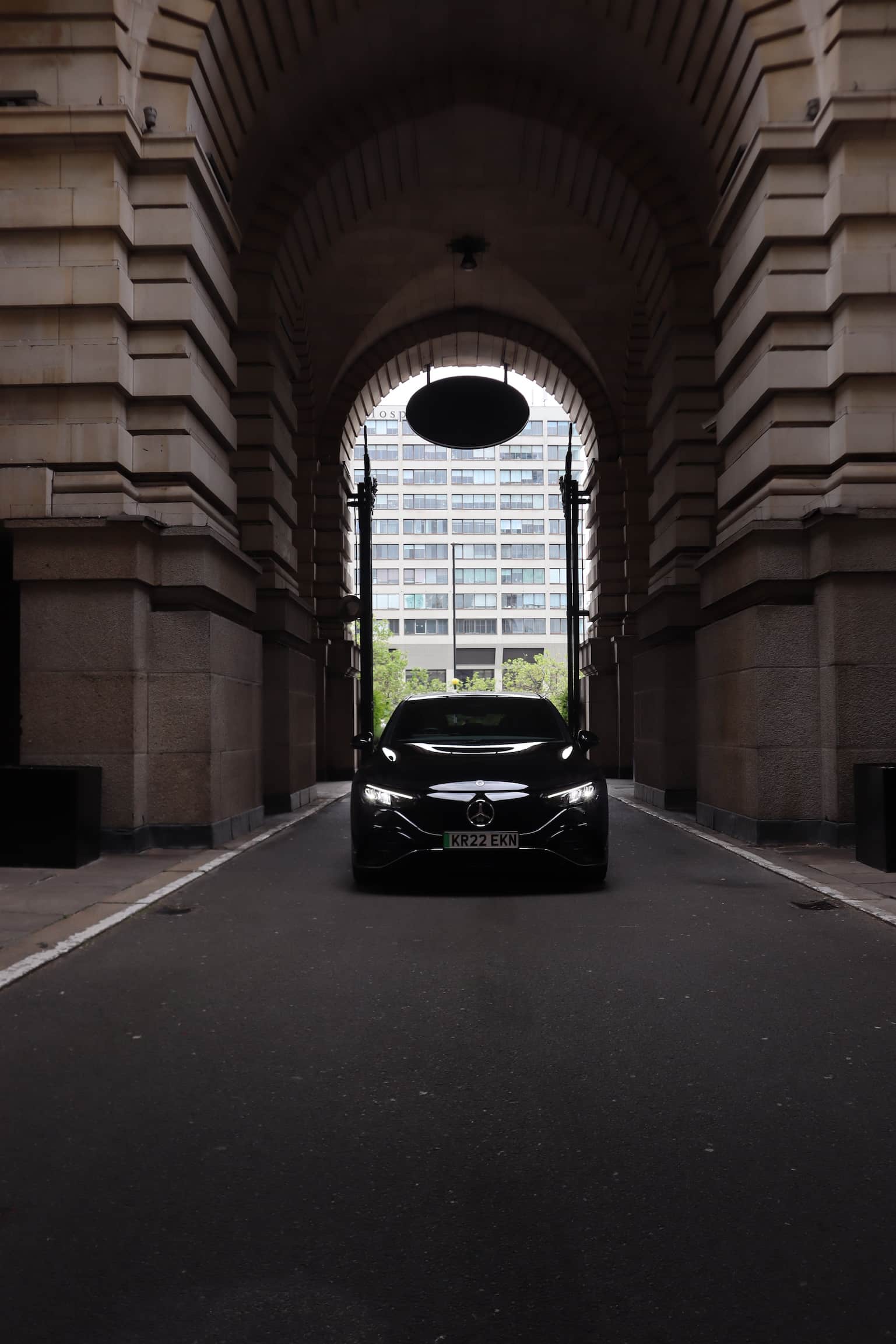 Who-we-are-section/About-Us A black car stands still in a tunnel, with shadows cast by the tunnel's structure creating a dramatic effect.