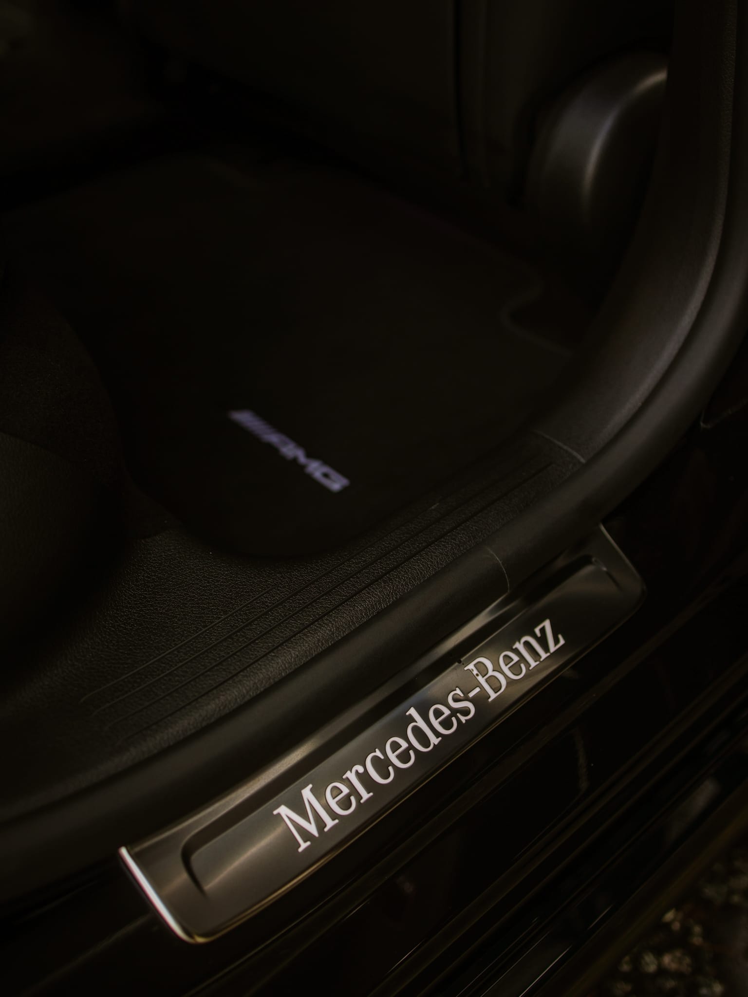 Close-up of a black car door handle featuring the Mercedes logo prominently displayed