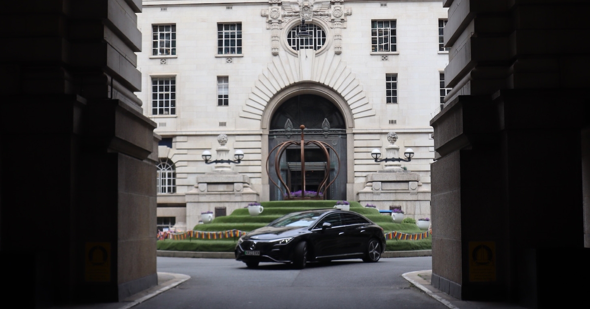 A black car stands still in a tunnel, with shadows cast by the tunnel's structure creating a dramatic effect.
